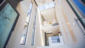 A modern interior with a glass facade, a balcony with a railing, and a reception desk with a vase of flowers. - C' la Vie Melkbos (Cape Town)