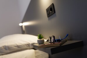 A neatly arranged bedside table with a small potted plant, a pair of glasses, and a book. - Pensión Dorotea (Santiago de Compostela)