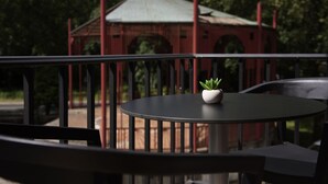 Een ronde tafel met een bloempot, een metalen hekwerk en een tuinpaviljoen op de achtergrond.