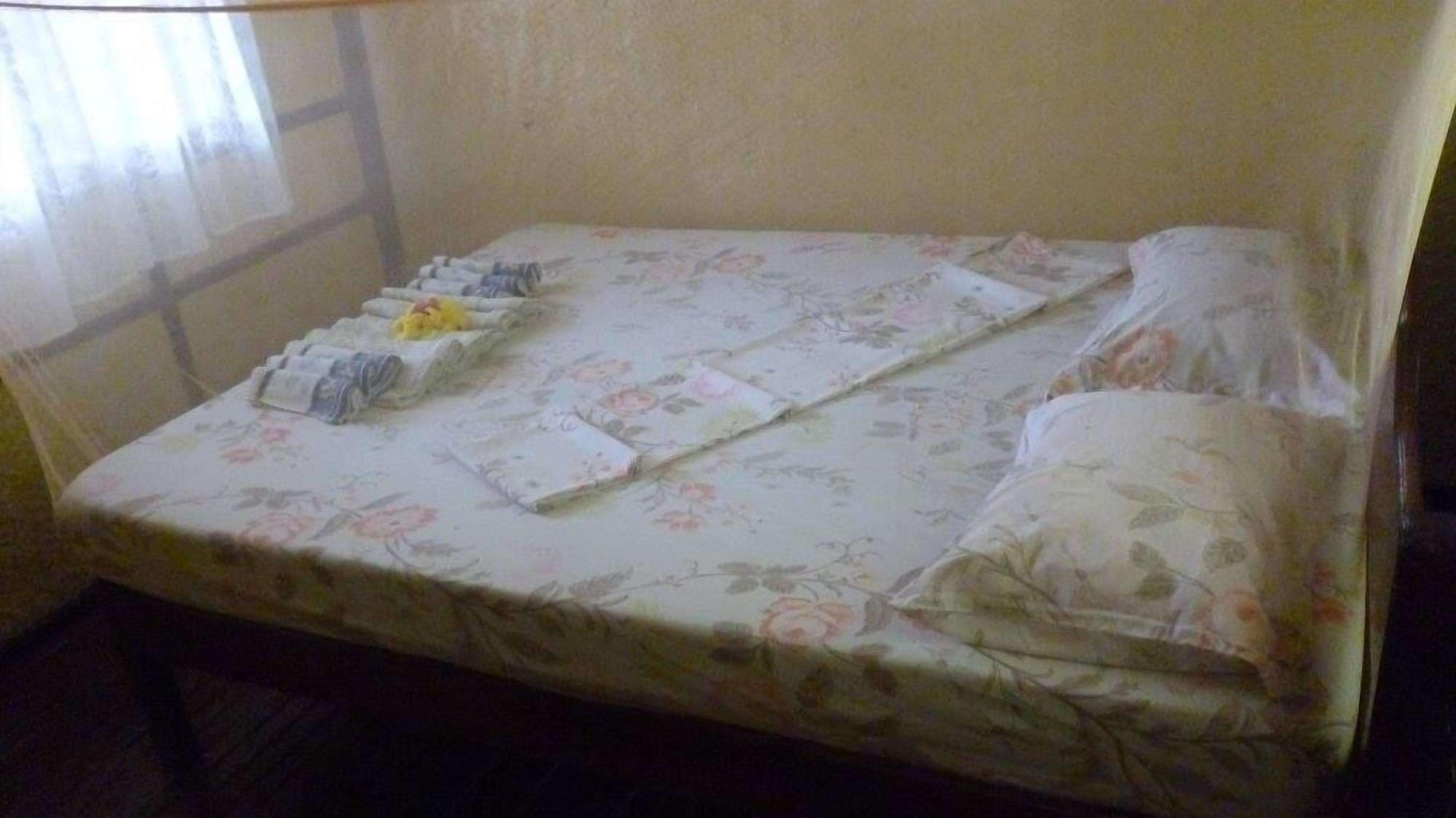 A small, single-bed room with a floral-patterned bedspread and a plain wall.