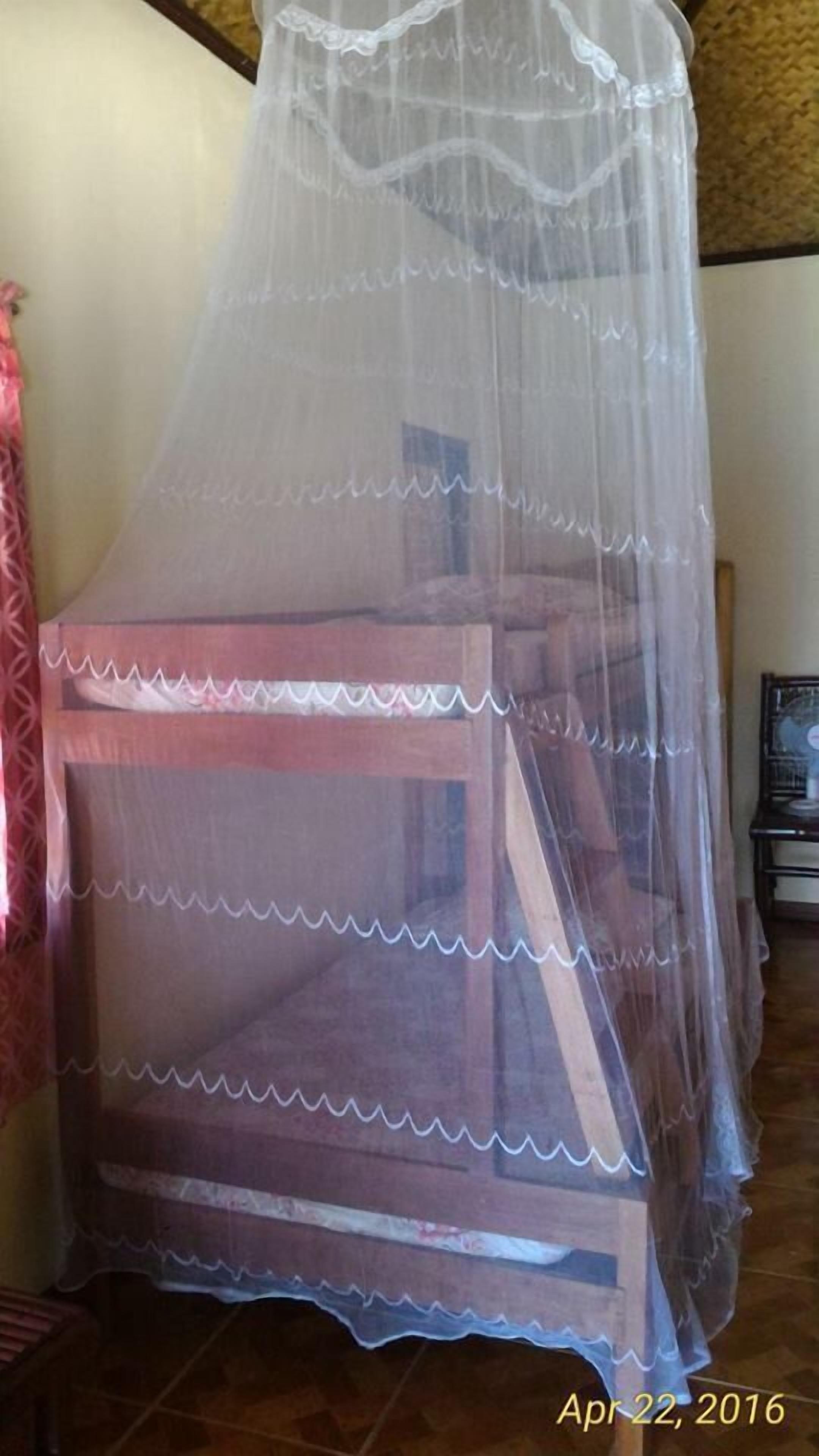Una habitación con una cama cubierta por una mosquitera.