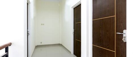 A hallway with white walls, a tiled floor, and two wooden doors with a horizontal line dividing them.