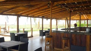 An outdoor bar area with wooden furniture and a thatched roof. - Samharam Resort Salalah (Salalah)