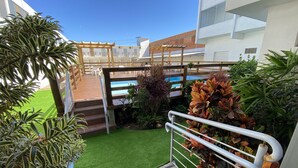 A rooftop terrace with a wooden pergola, artificial grass, and various potted plants. - Hotel Centenário (Tramandai)