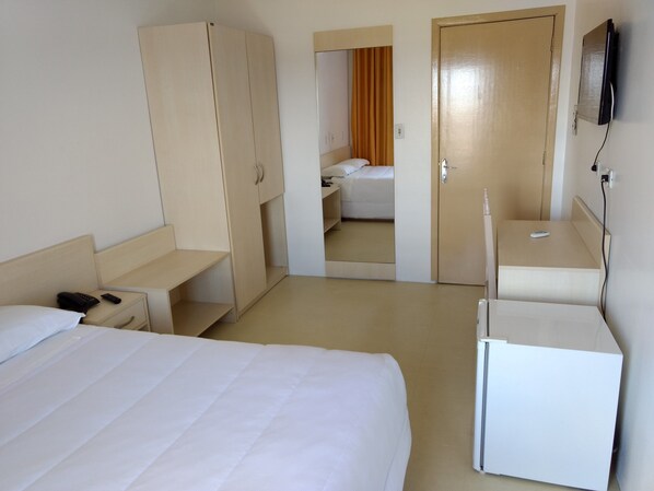 Une chambre d’hôtel comprenant un lit, une armoire, un bureau, un miroir et un téléviseur.