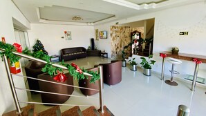 A spacious lobby with a staircase, a Christmas tree, a sofa, and a bar area. - Hotel Centenário (Tramandai)
