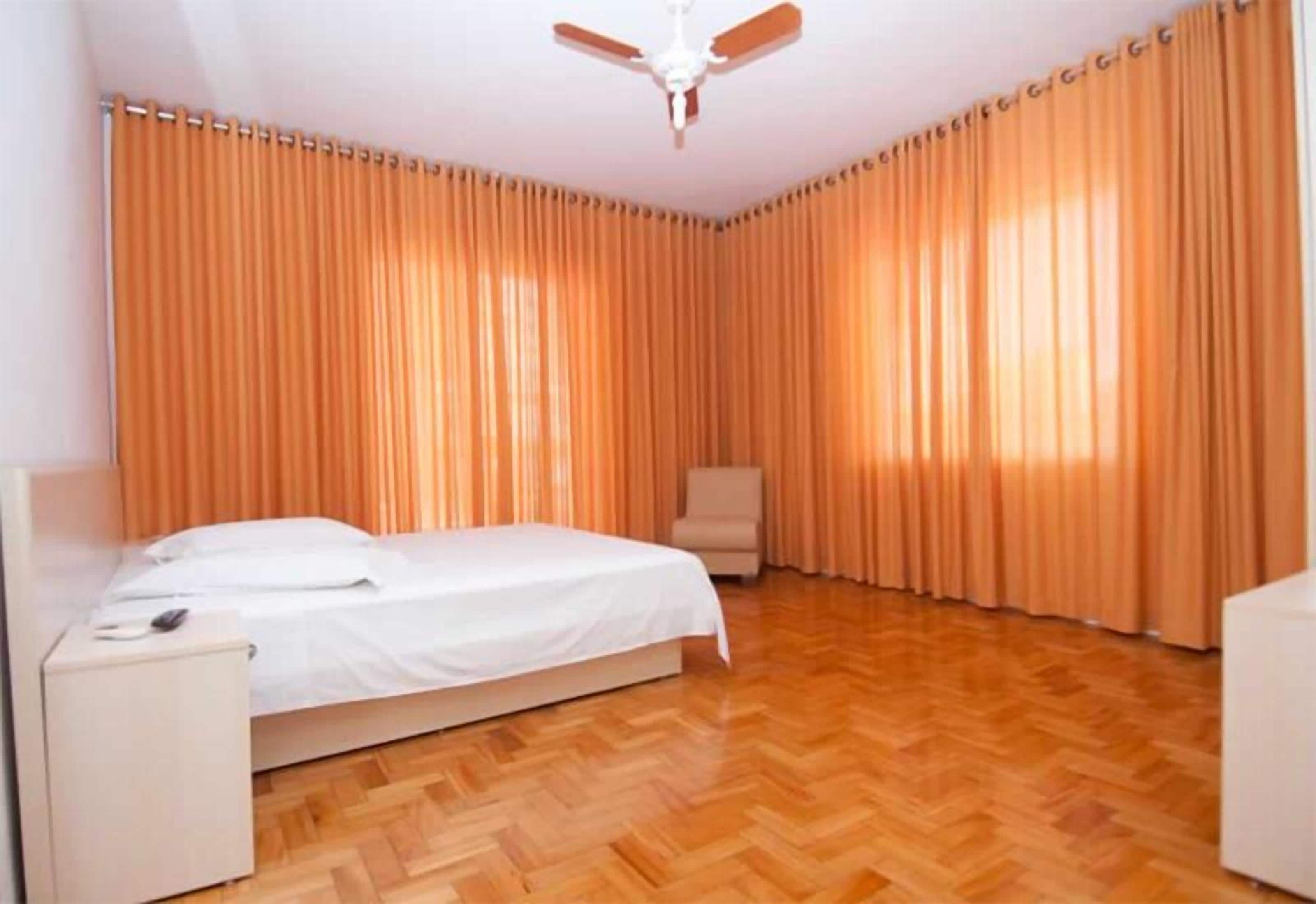 A bedroom with a bed, a chair, a desk, and a ceiling fan.