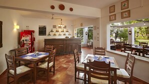 A restaurant with wooden tables and chairs, a bar area, and a view of the outdoors. - O Pescador (Panaji)
