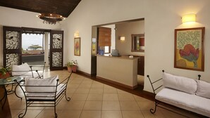A hotel lobby with a reception desk, a seating area with a sofa and chairs, a potted plant, and artwork on the walls. - O Pescador (Panaji)