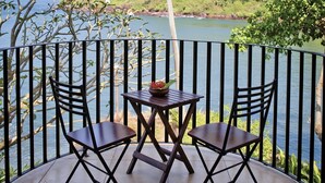A terrace with two chairs and a table, overlooking a body of water and greenery. - O Pescador (Panaji)