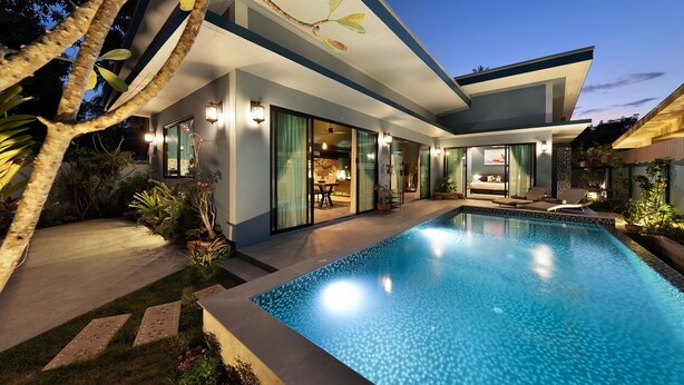 Una casa moderna con piscina, ventanas amplias y zona de estar exterior.