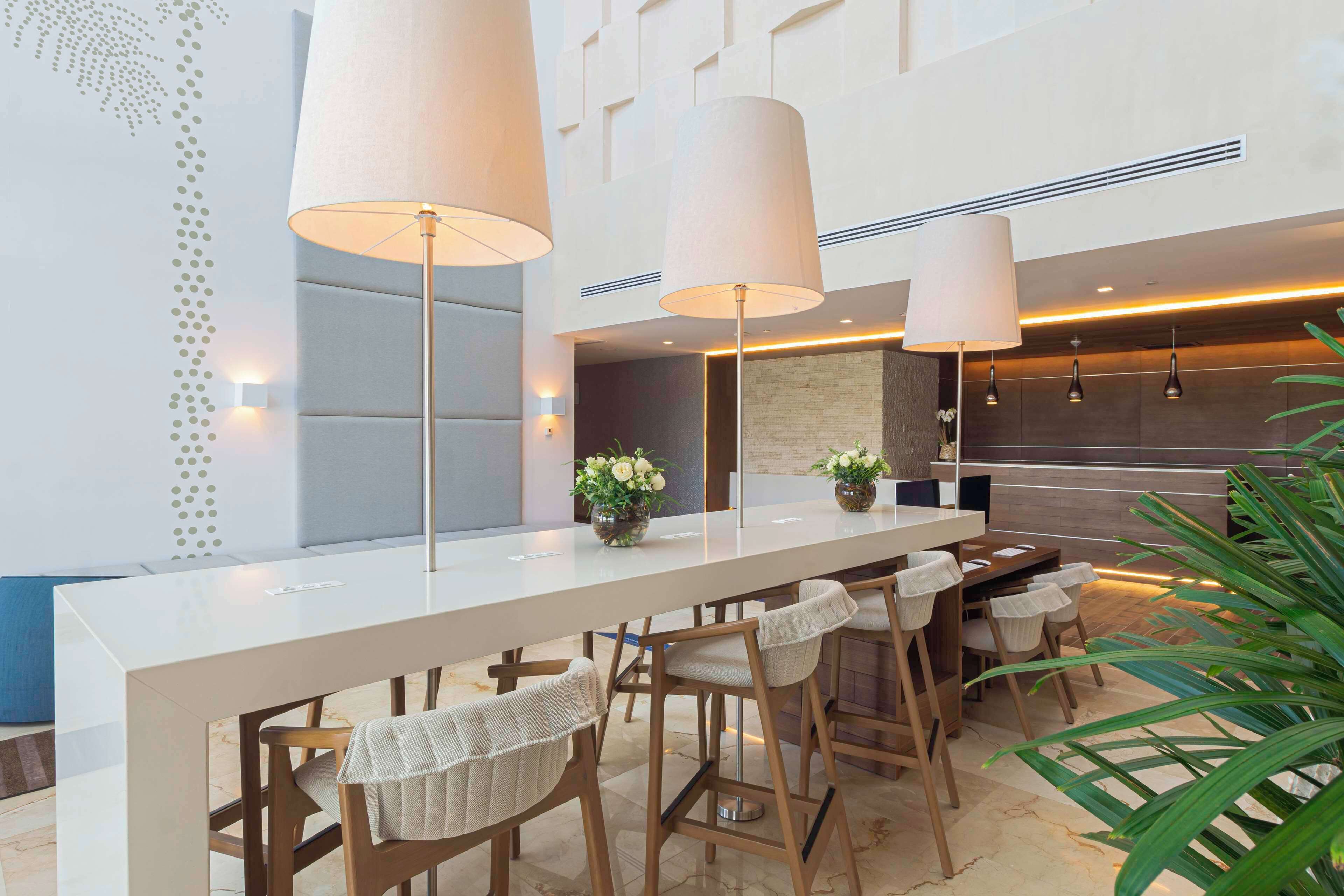 A modern bar area with a long counter, multiple bar stools, and pendant lighting.