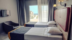 A hotel room with two beds, a chair, a television, and a view of the sea. - Simply Fine Hotel Alize - Adults Only (Alanya)