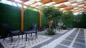 An outdoor patio area with a pergola, black chairs, a small table, and a hammock. - Simply Fine Hotel Alize - Adults Only (Alanya)