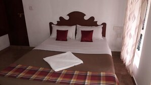 Una cama bien tendida con una manta escocesa y dos almohadas, un cabecero de madera y una ventana con cortinas.