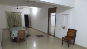 Una habitación amplia con una mesa de comedor y sillas, un ventilador de techo y una puerta que da a otra habitación.