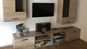 Uma sala de estar moderna com televisão de tela plana na parede, armários de madeira e um sistema de entretenimento embutido, com caixas de som e espaço para guardar objetos.