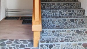 A wooden staircase with a stone-tiled landing area and a wooden handrail. - Beautiful vacation apartment in the countryside , pets welcome ❤️ (Häselgehr)