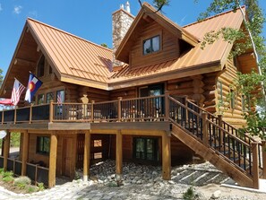 A log cabin with a balcony, a chimney, and a stone chimney base. - Secluded Custom Log Home w Hot Tub - by Winter Park, Granby Ranch & Grand Lake (Tabernash)