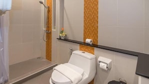 Ein Badezimmer mit Dusche, Toilette und Ablage für Pflegeprodukte.