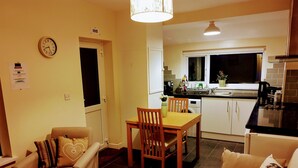 A compact living space with a dining area, a sofa, and a kitchenette. - The Hazeldene Apartment (Cardiff)