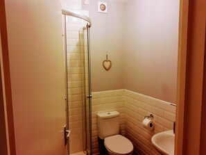 A small bathroom with a glass shower enclosure, a toilet, and a sink. - The Hazeldene Apartment (Cardiff)