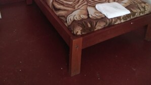 A single bed with a wooden frame, white bedding, and a tiger-patterned bedspread. - Mt Kenya Safari Halt Hotel (Chaka)