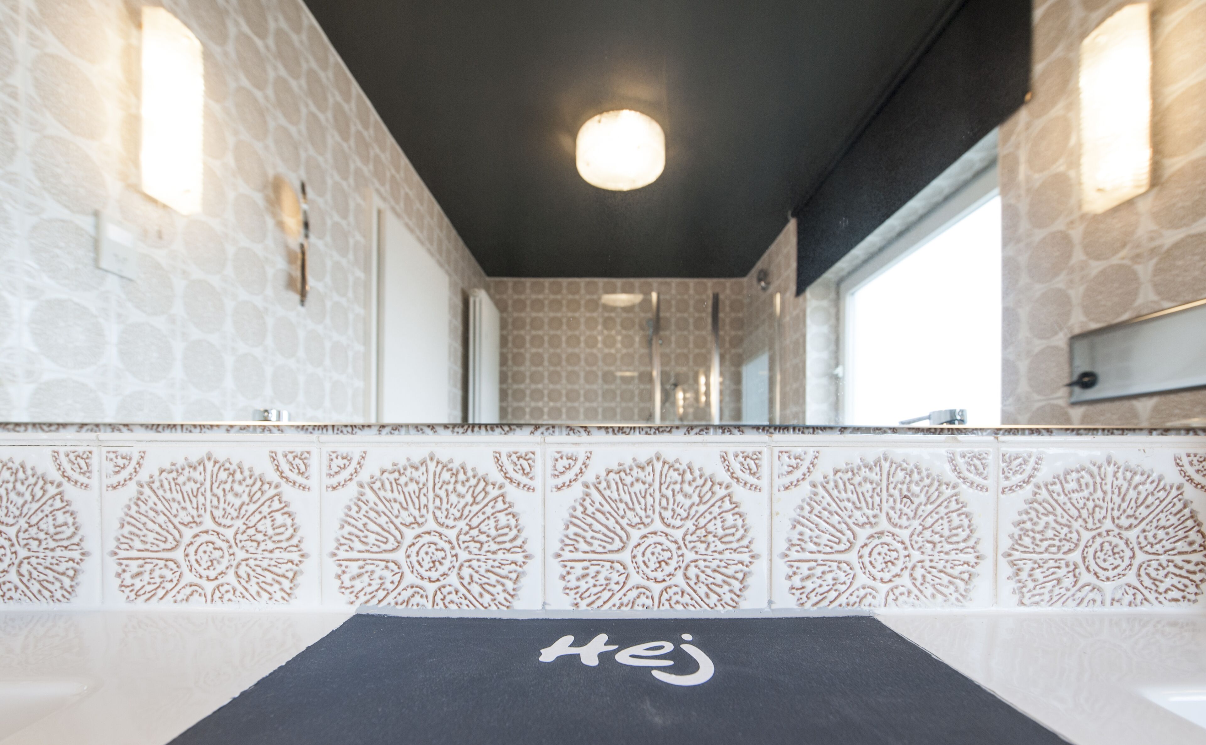 A bathroom with patterned tiles, a black towel, and a mirror.