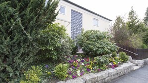 Um edifício com um muro de pedra e diversas plantas floridas.