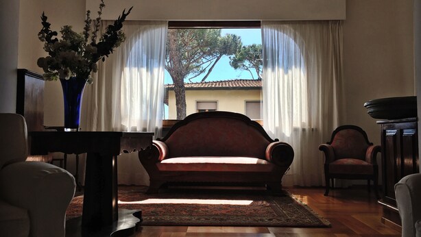 Uma sala de estar com sofá, cadeiras, uma mesa e um vaso de flores.