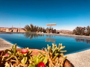 Una piscina al aire libre, una piscina con borde infinito, tumbonas