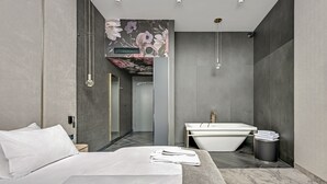 Et moderne hotelværelse med en stor seng, et badeværelse med badekar og bruser.