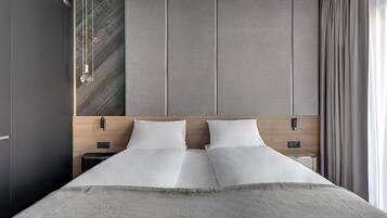 A modern hotel room with a large bed, a wooden headboard, a nightstand, and a small table.
