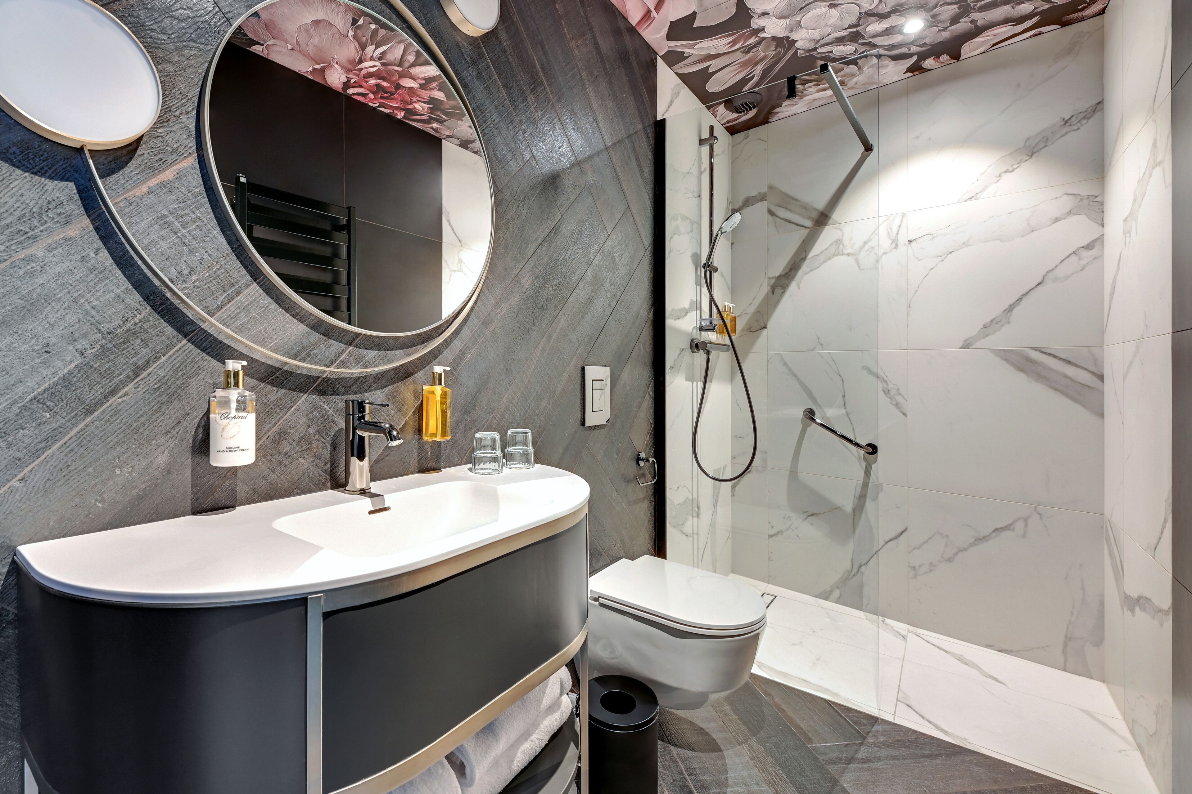 Un baño moderno con tocador, lavabo, espejo, inodoro y ducha.