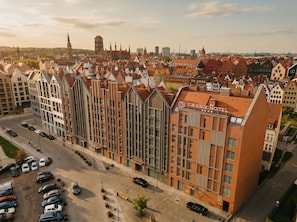 Un hotel moderno con un letrero llamativo, rodeado de arquitectura europea tradicional.