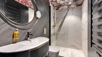 Ein modernes Badezimmer mit einem geschwungenen Waschtisch, einer Toilette und einer Duschkabine.