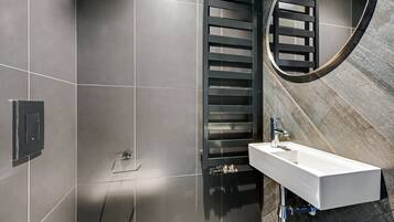 Une salle de bain moderne avec un lavabo rectangulaire, un porte-serviettes et un espace douche.