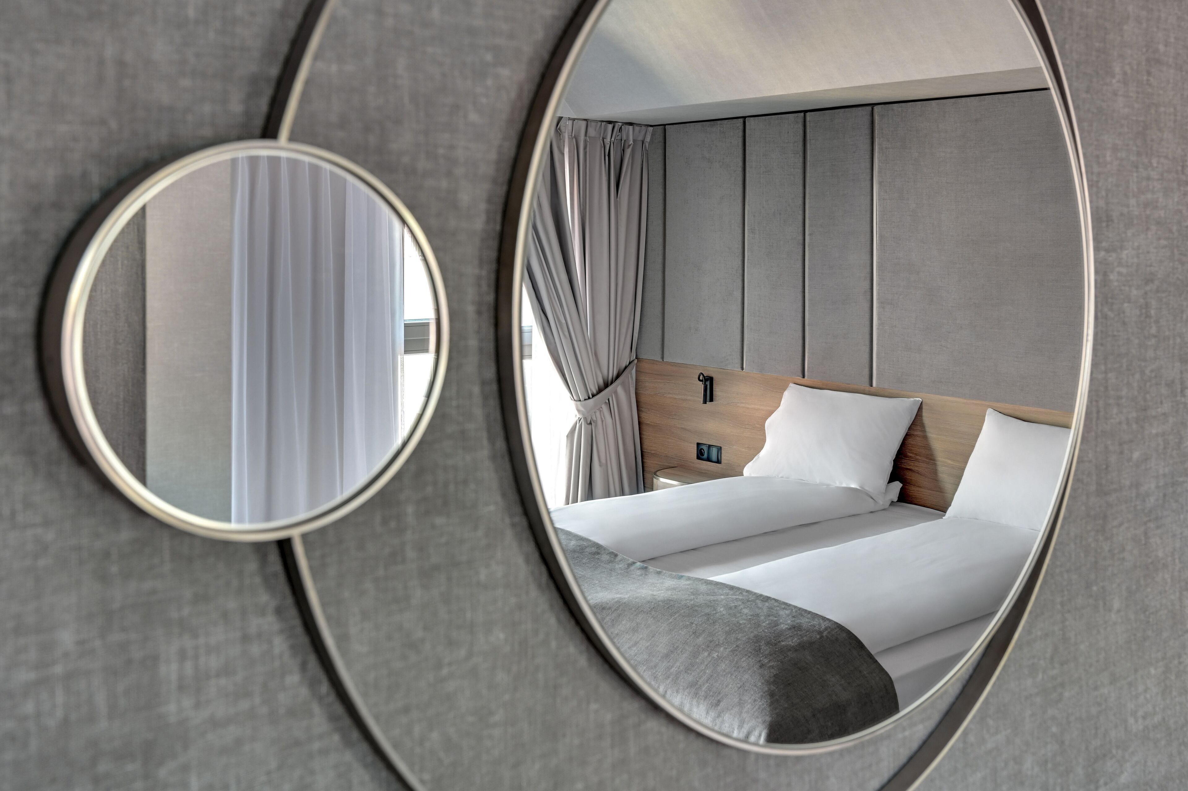 Moderni hotellihuone, jossa on suuri sänky, yöpöytä ja peili.