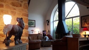 Een gezellige woonkamer met een stenen muur, een open haard, leren banken en een groot raam.