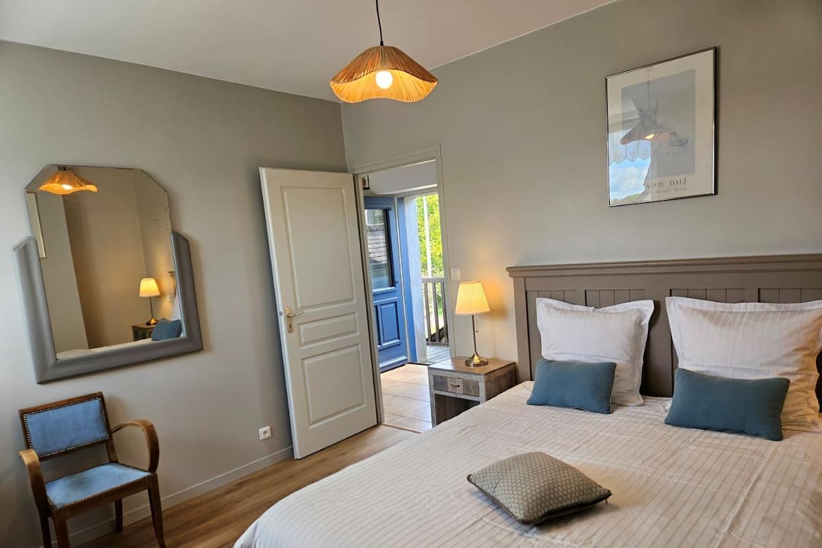 Een slaapkamer met een bed, bedlampen, een stoel, een spiegel en een deur naar een balkon.