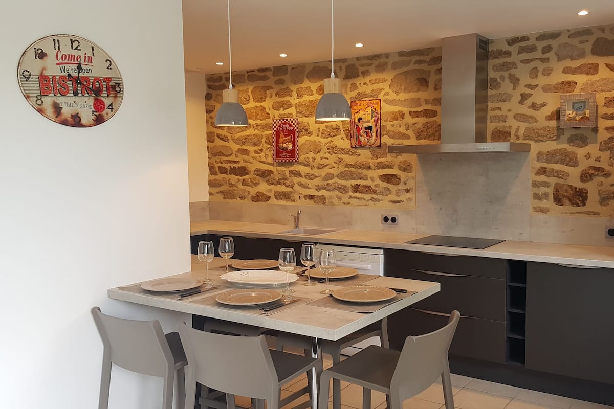 Een moderne keuken met een spatwand van natuursteen, een inbouwoven en hanglampen.