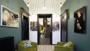 A hallway with green armchairs, a radiator, and framed pictures on the walls. - Le Boutik Hotel (Annecy)