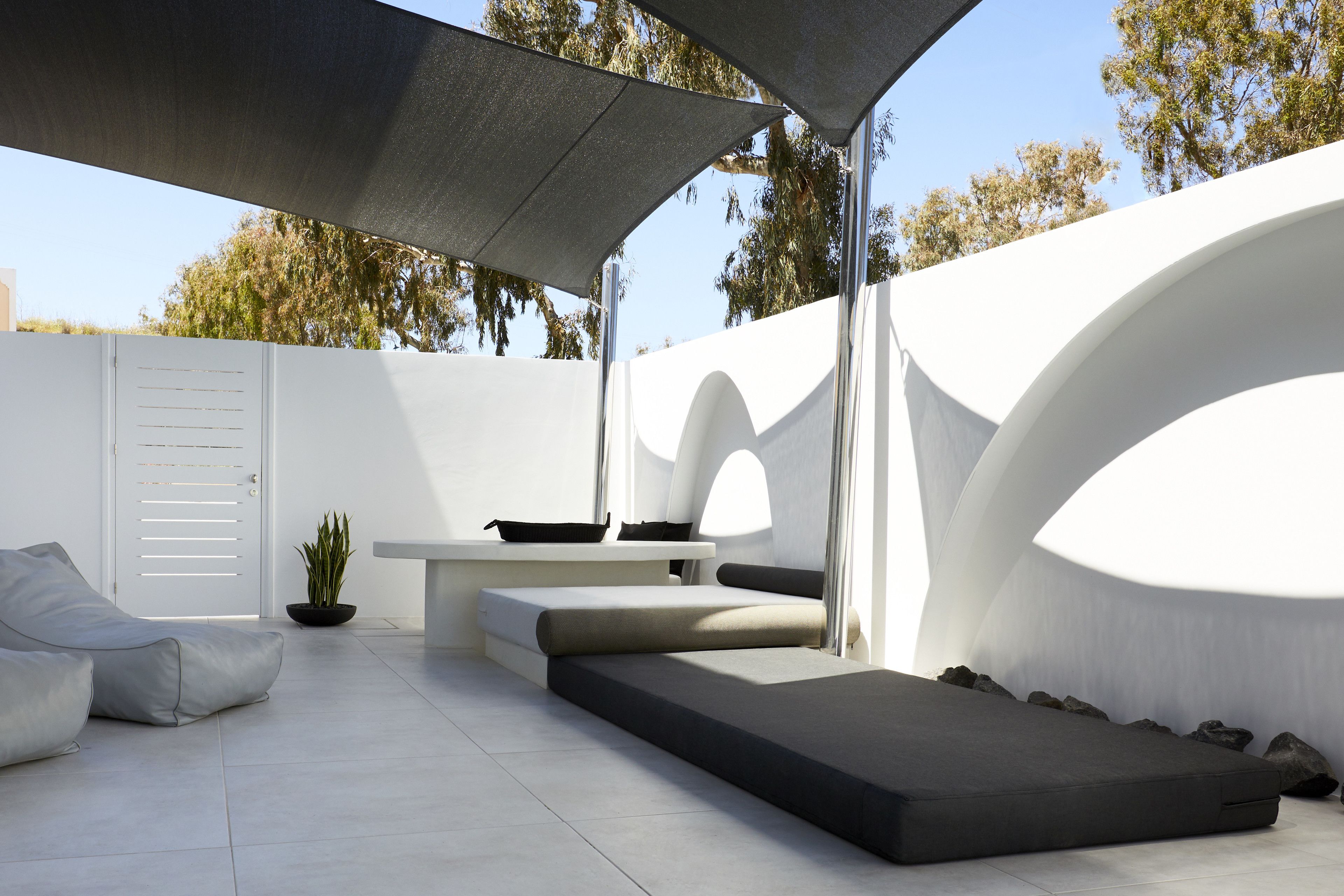 A modern outdoor seating area with a sofa, a bench, and a table.