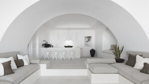 Un intérieur moderne avec un plafond incurvé, un espace cuisine central et des coins salon.