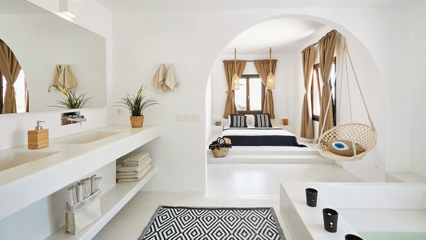 Une salle de bain moderne avec un grand miroir, un meuble-lavabo blanc et une chaise suspendue.