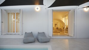 Un intérieur moderne avec une piscine, deux fauteuils en forme de poire de couleur grise et une pièce bien éclairée, comprenant un canapé et un tapis rond.