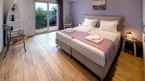 A bedroom with a large bed, a chair, a small table, and a balcony. - Villa Alba with Private Pool & SeaView (Apolpena)