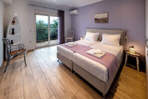 Une chambre avec un grand lit, une chaise, une petite table et un balcon.
