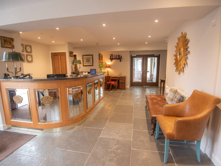 A spacious living area with a curved wooden coffee table, a brown leather sofa, and a dining table with chairs.