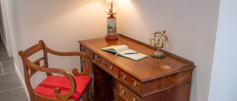 A wooden desk with a red cushioned chair, a lamp, and a globe ornament.